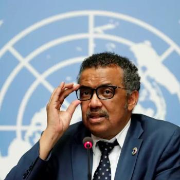 Dr Tedros Gebreyesus sits in front of the UN coat of arms